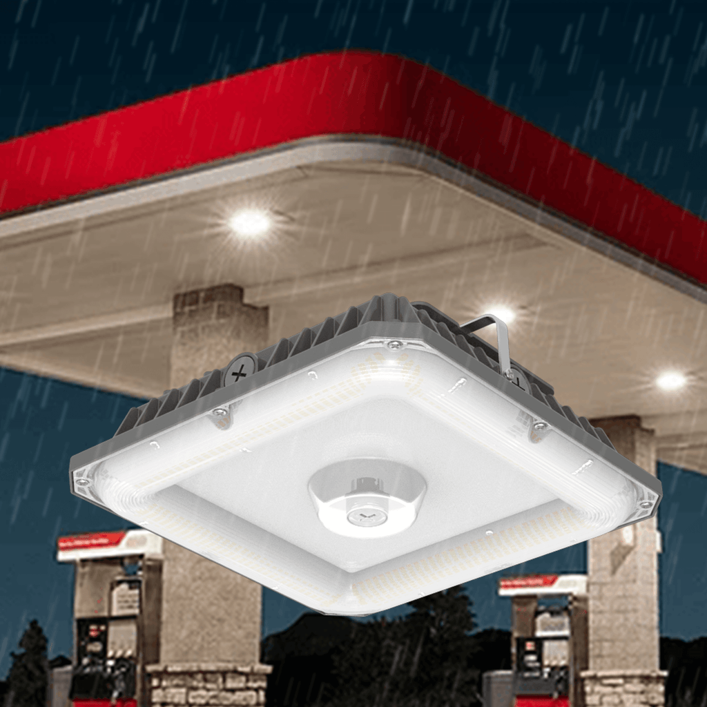 AEH5 LED Gas Station Canopy Light IP65 Waterproof Installed Under Red Canopy Roof in Heavy Rain Showing Square Aluminum Housing with Microwave Sensor and Bright LED Panel for Outdoor Petrol Station Use
